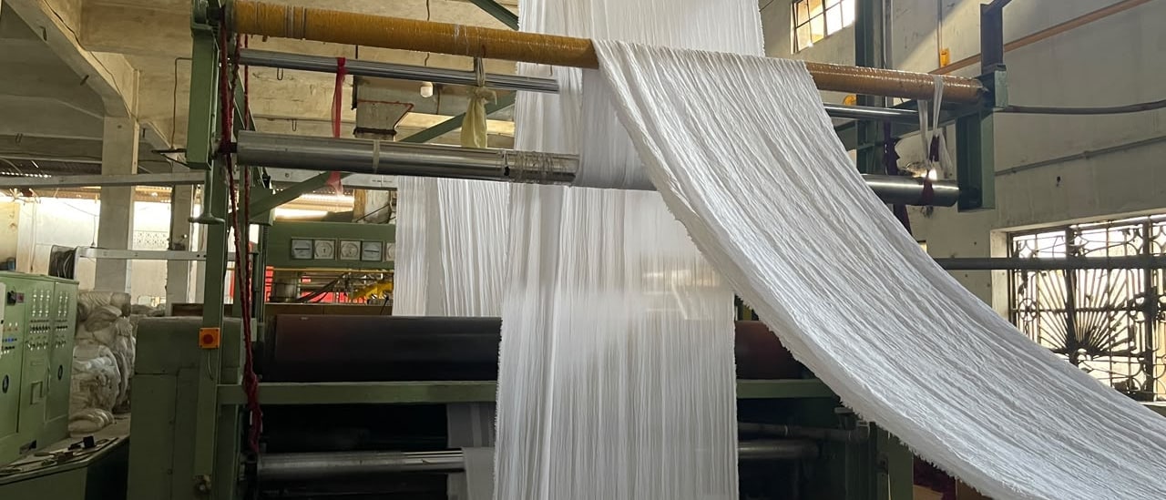 White fabric moving through the preparation line at AL-KHAIR DYEING.