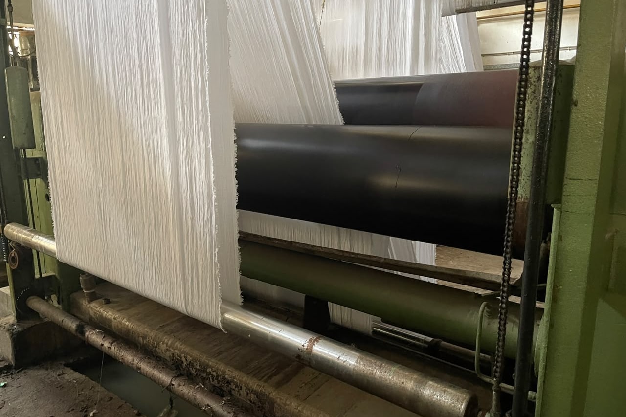 Prepared white fabric on the roller system before the next stage.